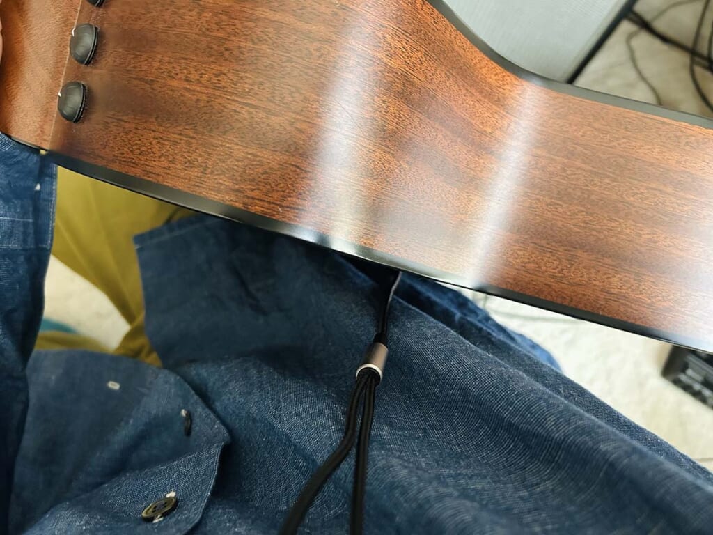 アコギと体の間にケーブルが入り込んだ状態